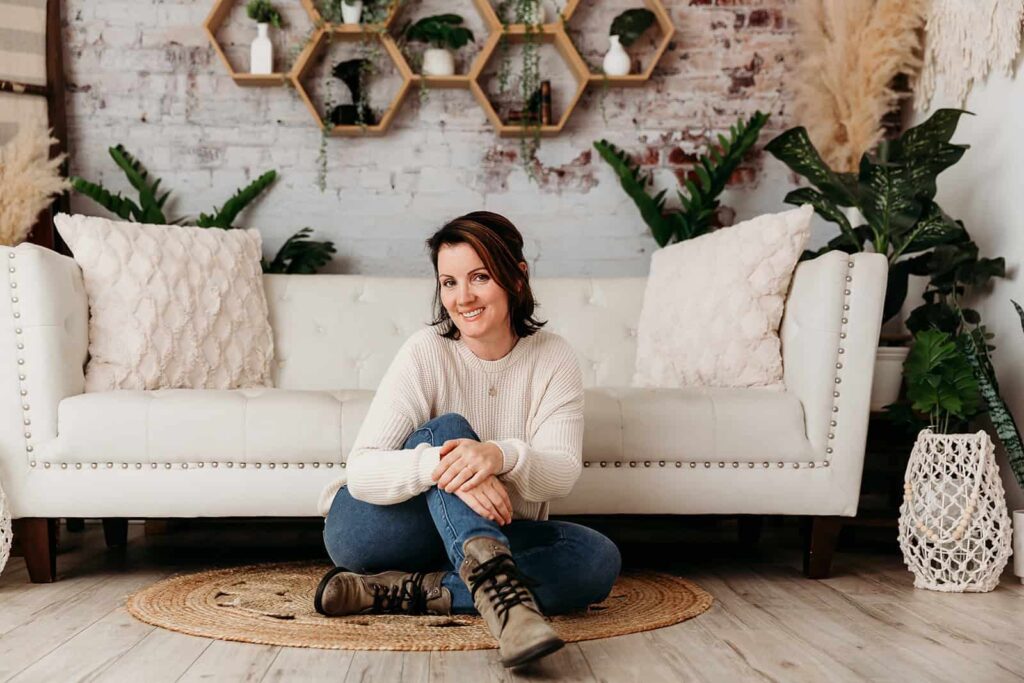Marika Ydenberg of Marketing Mavens Sitting infront of couch